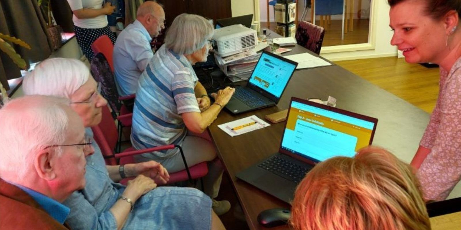 Personen zitten aan een tafel met laptops