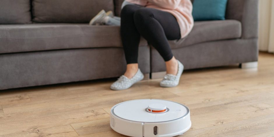 Vrouw met kind op de bank, ze kijken naar een robotstofzuiger