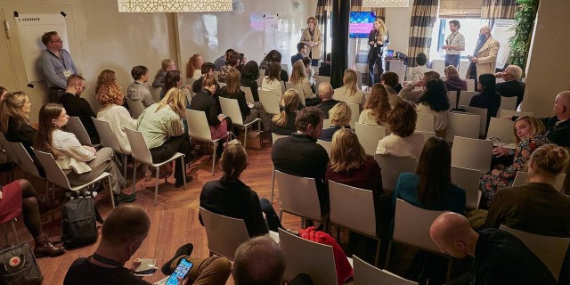 Deelnemers zitten in een ruimte in theater-opstelling