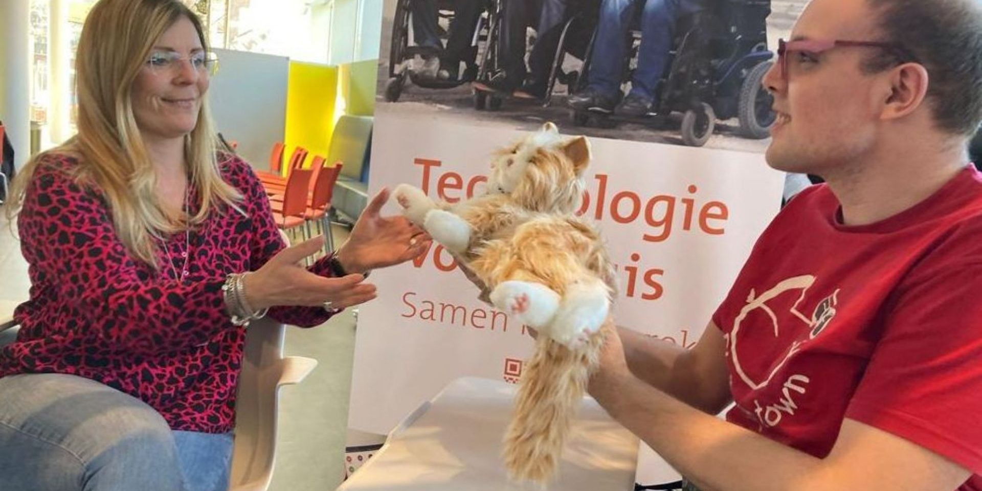 Man overhandigt robotkat aan vrouw tegenover hem